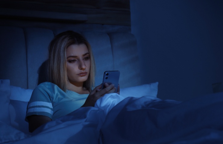 Una donna a letto con lo smartphone