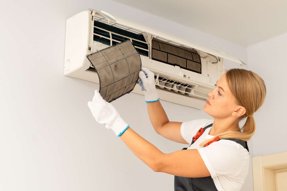 Una donna che smonta un condizionatore
