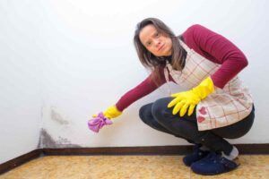 Una donna che indica della muffa su una parete