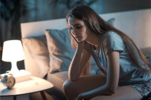 Ina ragazza che non riesce a dormire seduta sul letto