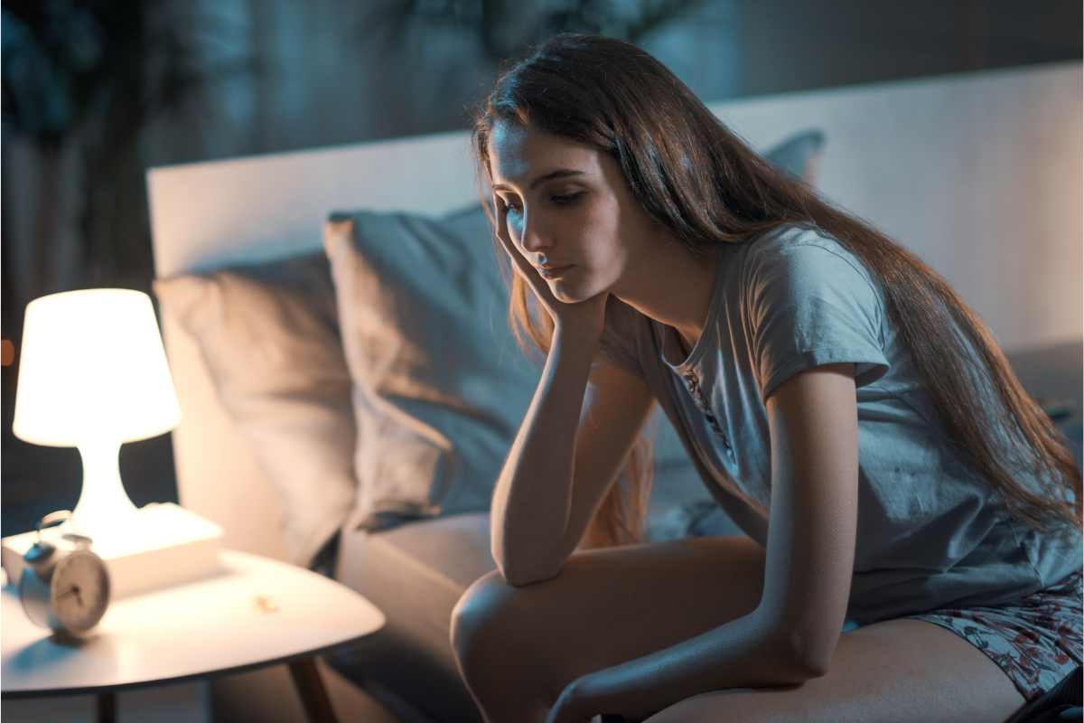 Ina ragazza che non riesce a dormire seduta sul letto
