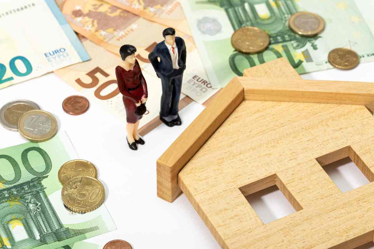 casetta, miniatura persone e soldi in contanti