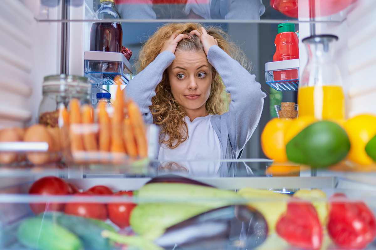 donna disperata guarda nel frigorifero