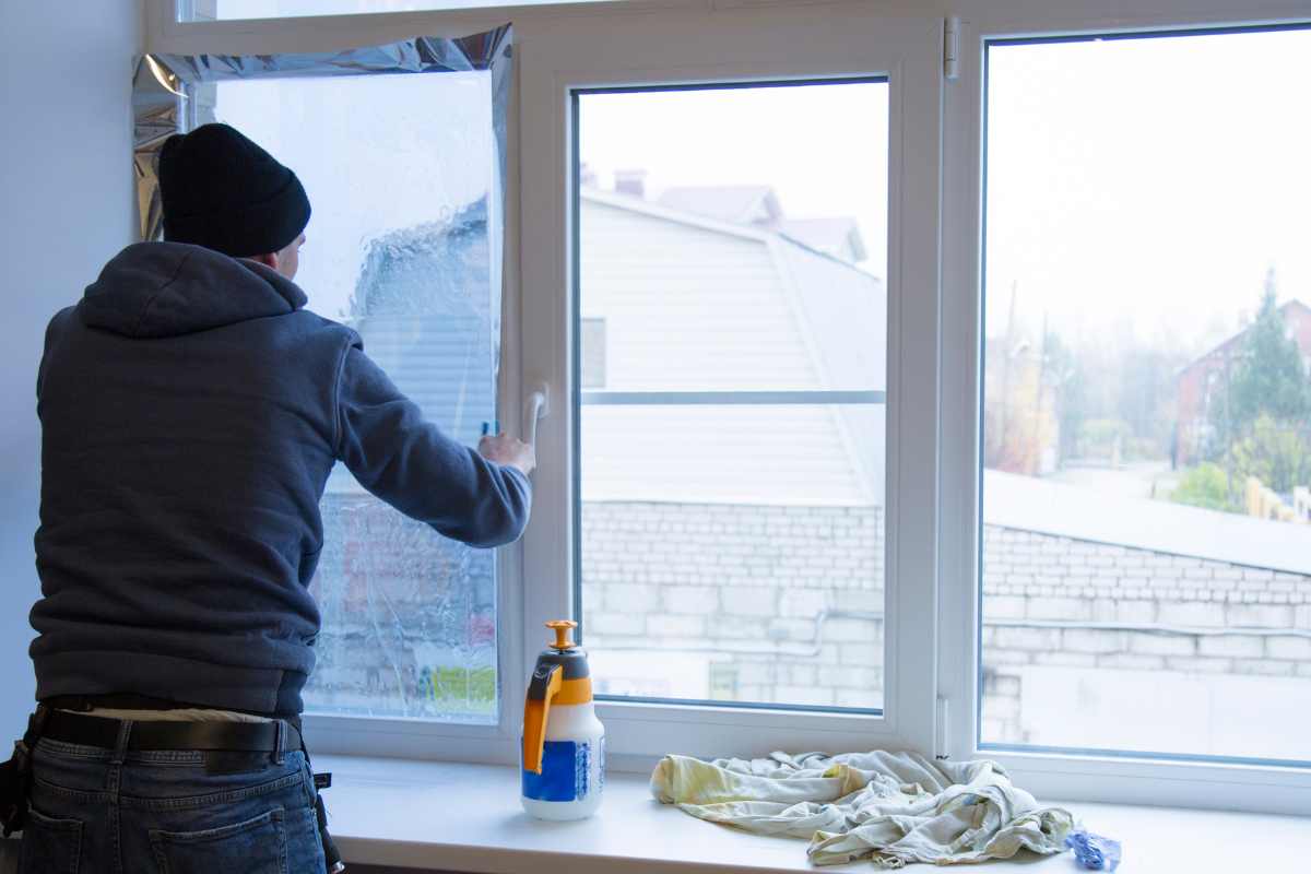 ragazzo che applica la pellicola alle finestre